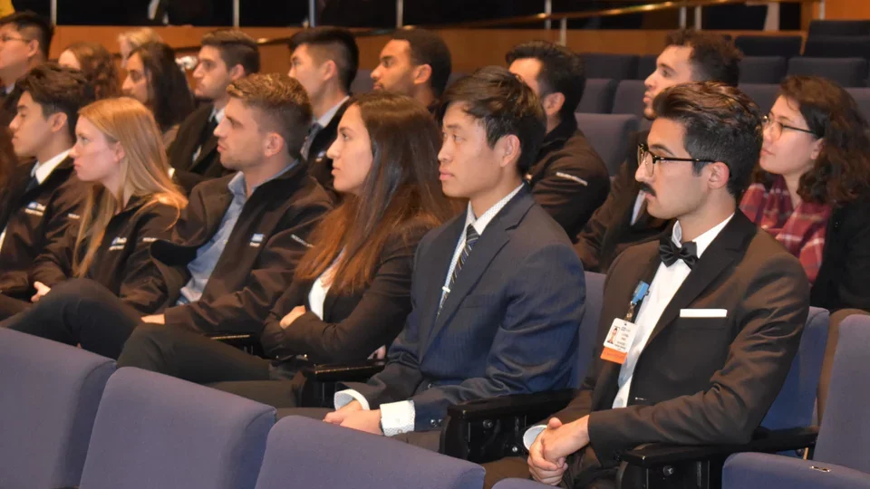 Research Associates members seated in an auditorium, listening to a presentation.