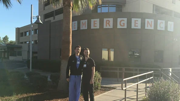 Two medical professionals standing outside an emergency department.