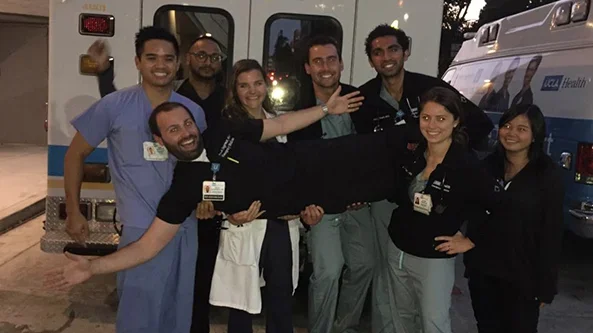 A group of medical professionals gathered in front of a UCLA ambulance.