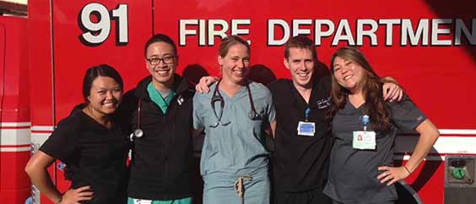 A group of five people, consisting of emergency medical staff, standing in front of a Los Angeles Fire Department ambulance.