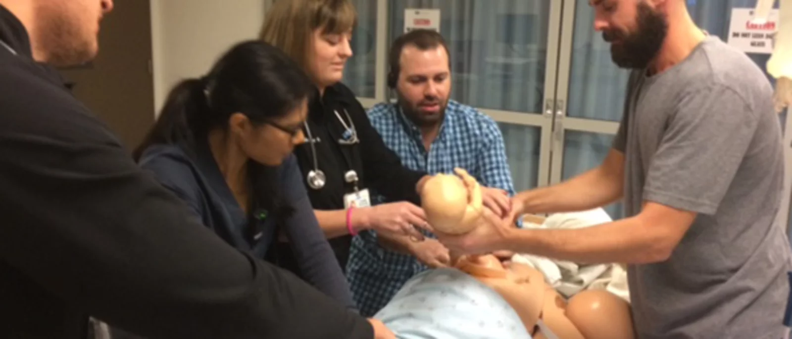 A group of medical professionals in a training scenario involving mannequins. 