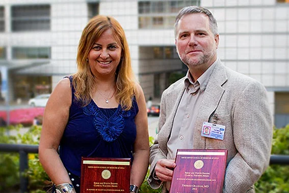 Two people hold awards