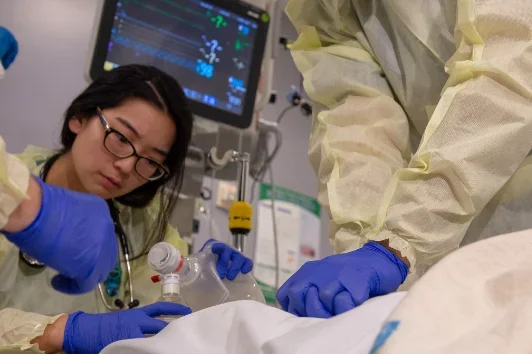 A medical team in a hospital setting, wearing protective gear including gowns, gloves, and masks. 