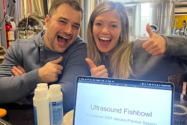 Drs. Sholder and Bass (2026) practice ultrasound for the upcoming SonoGames at a local brewery