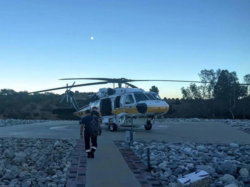 Helicopter on a helipad, with a person walking towards it. 