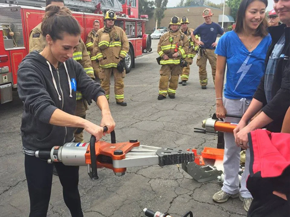 Group of people participating in a demonstration of a large hydraulic rescue tool known as the "Jaws of Life"