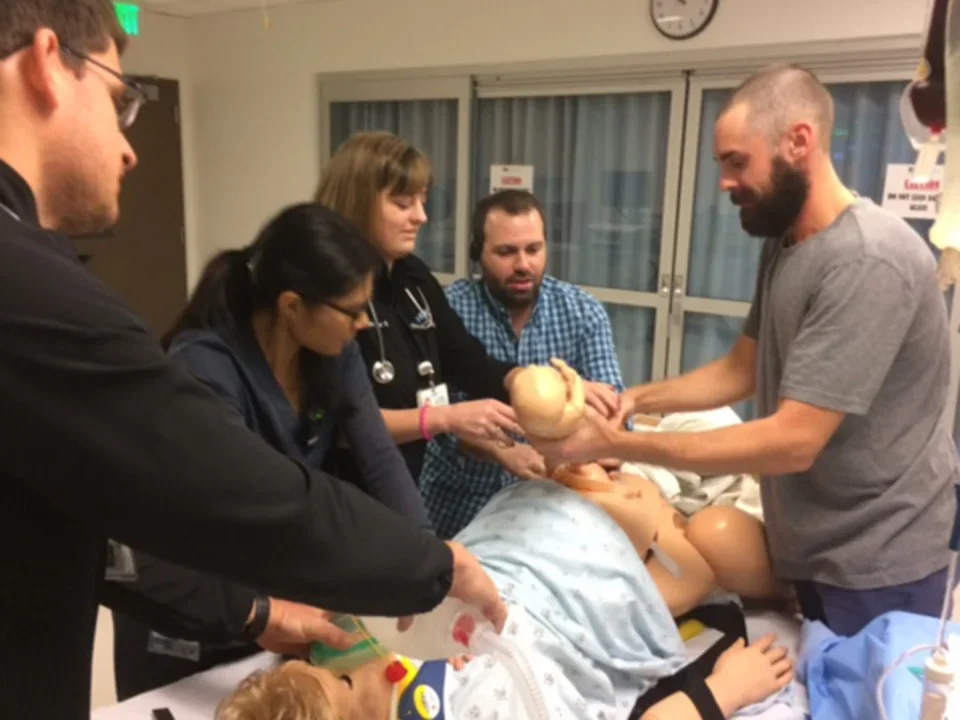 Students practice delivering a baby using medical dummies