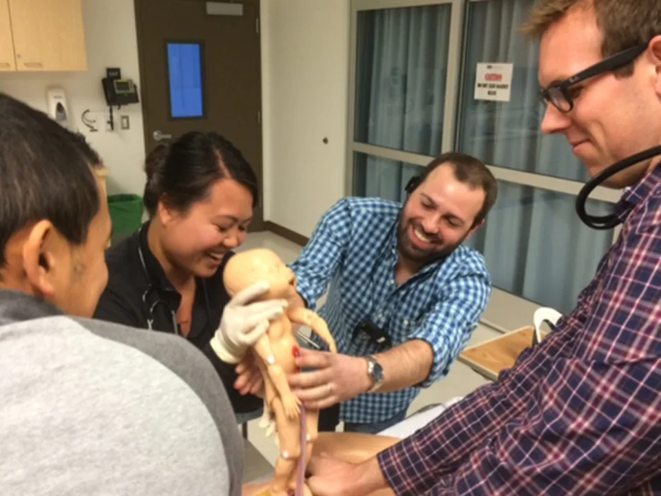 Students practice delivering a baby using medical dummies