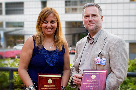 Two people hold awards