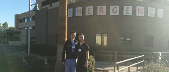 Two medical professionals standing outside an emergency department.