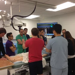 A group of medical professionals gathered around a hospital bed for simulation